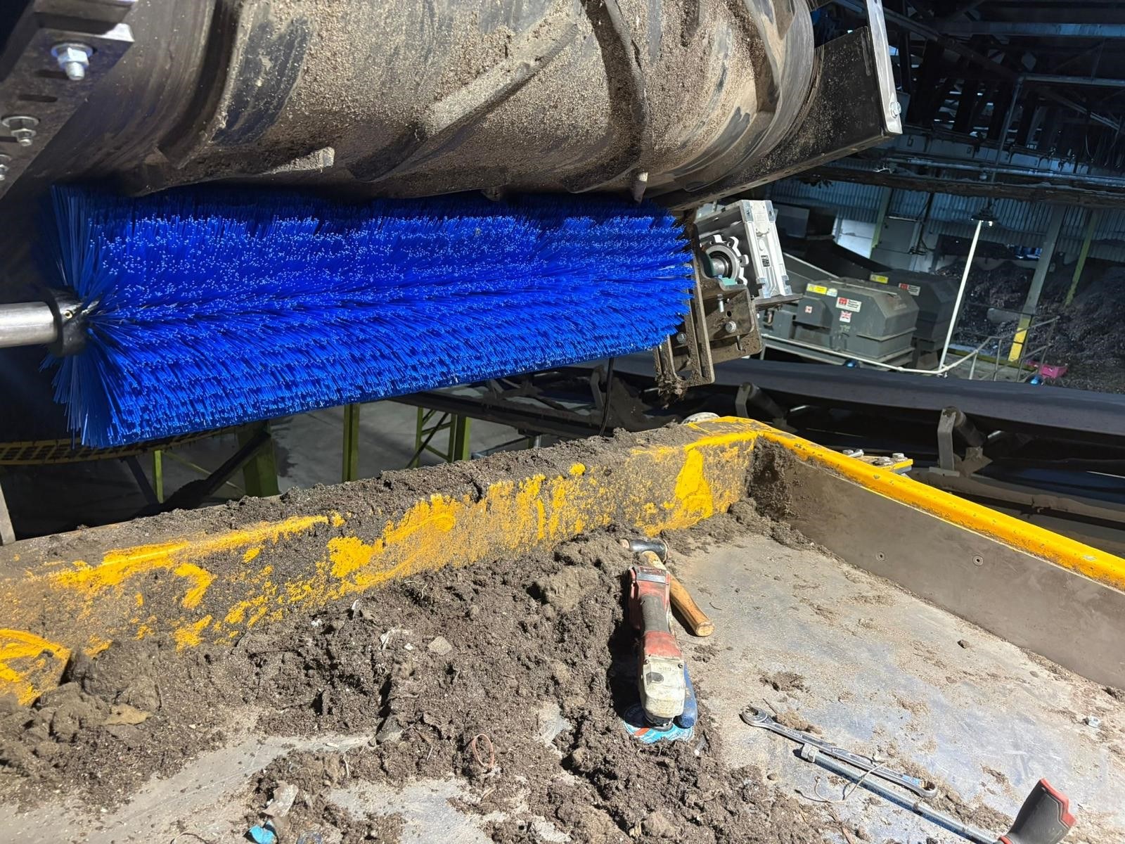 Blue rotary brush scraper cleaning a conveyor belt on site